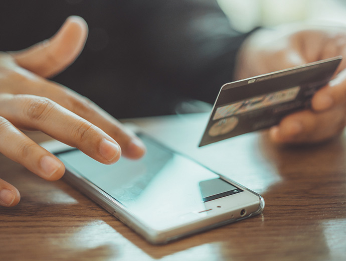 Person holding a credit card with their phone.